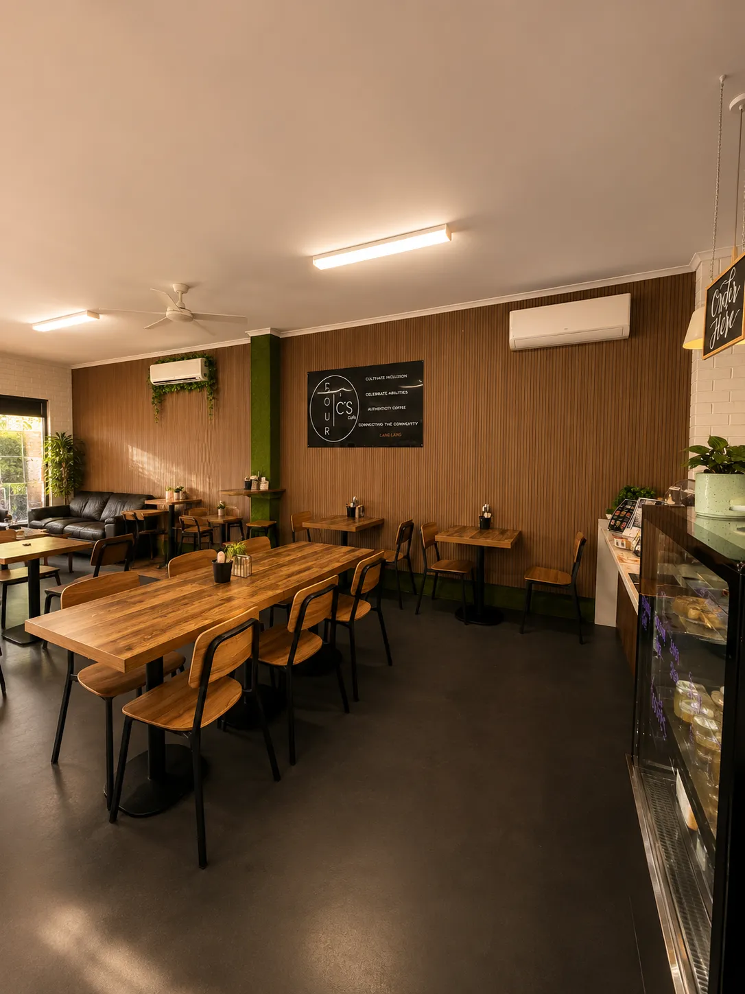 Four C's Cafe dining room with timber tables, black chairs, and warm timber feature wall