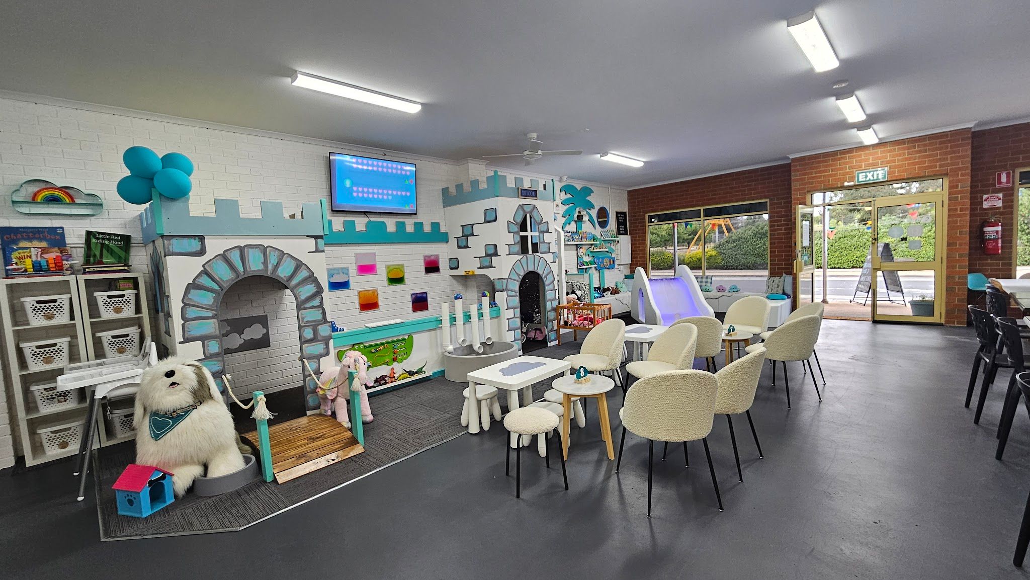 Four C's Cafe interior showing castle play structure, ball pit, boucle seating and outdoor playground